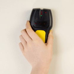 A stud finder being used on a wall